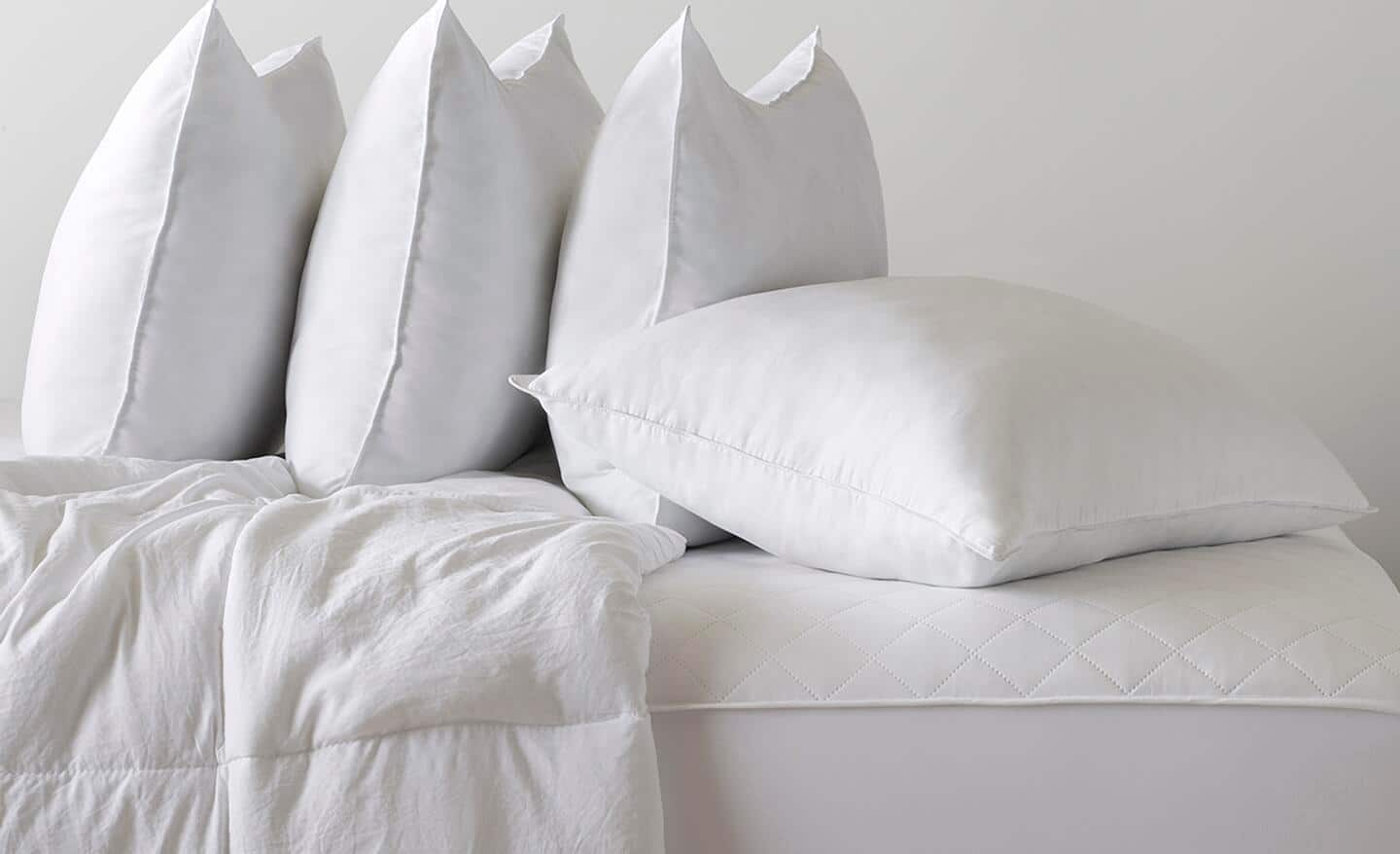 Several king pillows stacked on a bed.