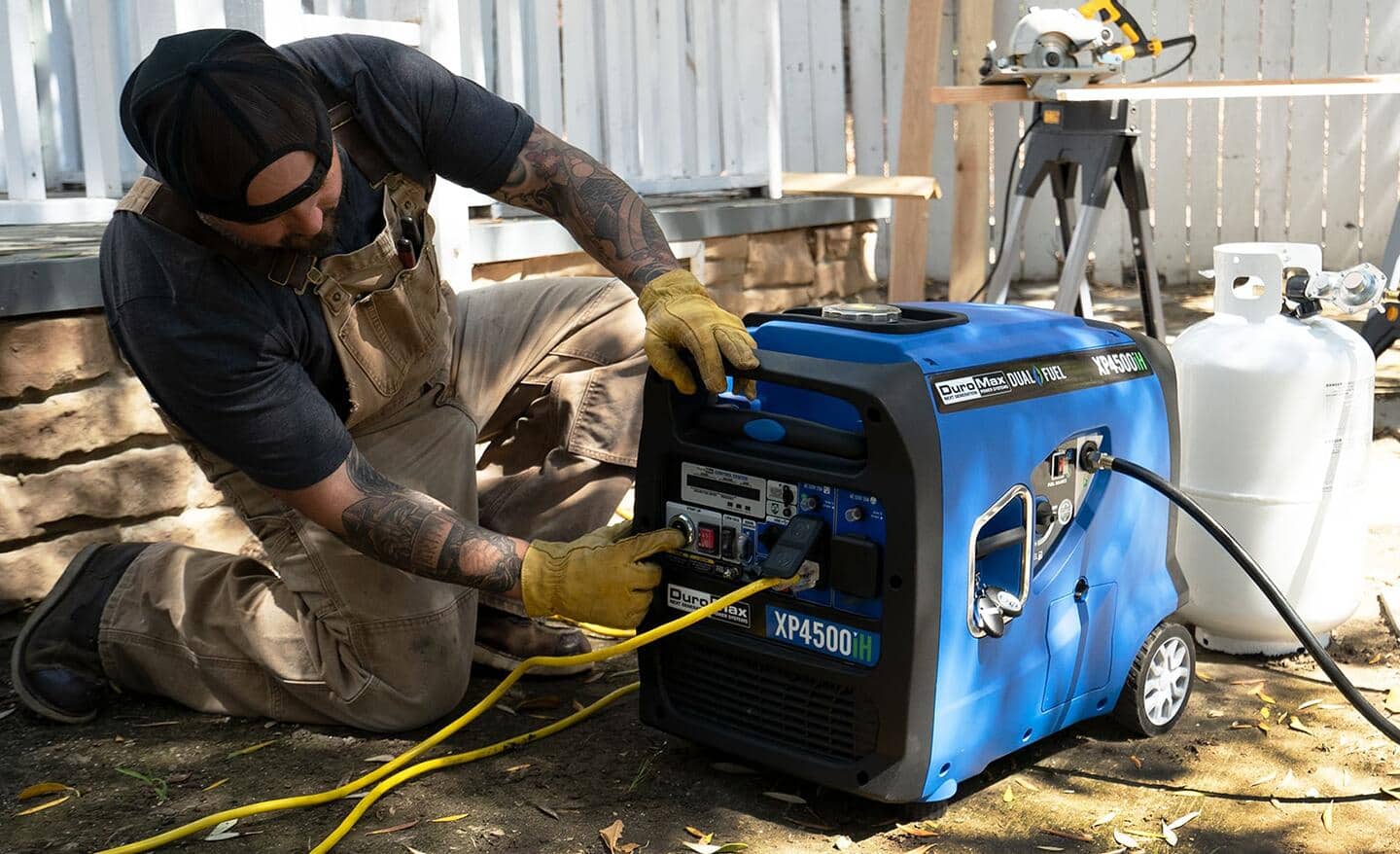 A man kneels down with both hands on a generator.
