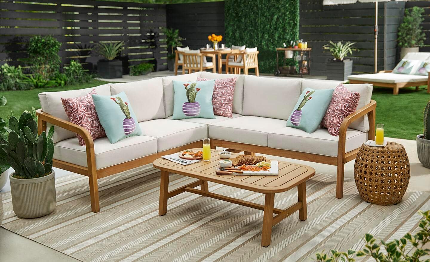 Wooden sectional sofa with off-white cushions and decorative pillows on a patio.