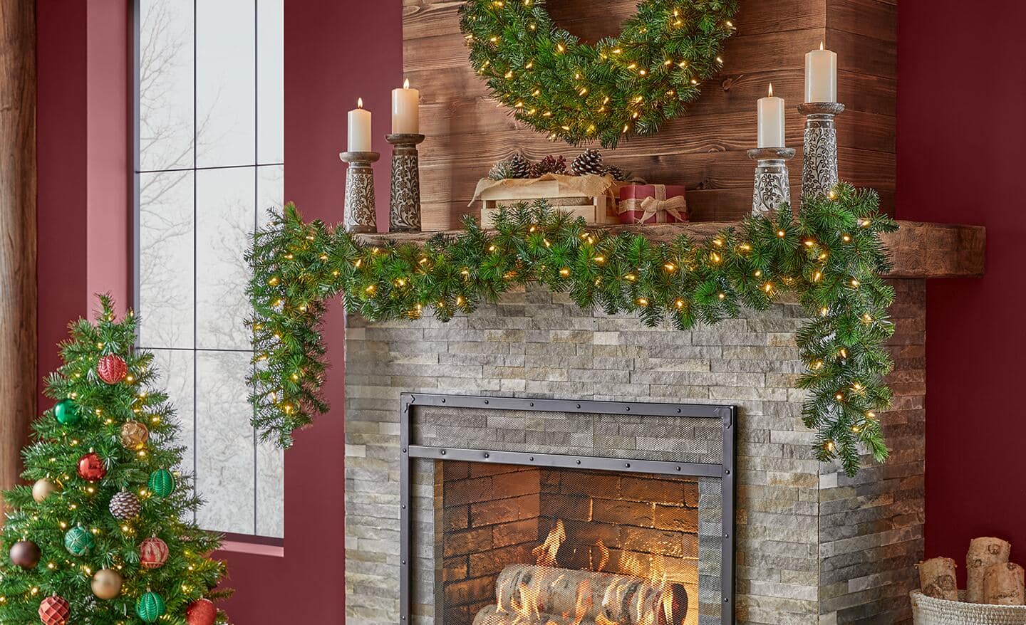 A wreath and garland made of greenery accent a stone fireplace. A wreath and garland made of greenery accent a stone fireplace.