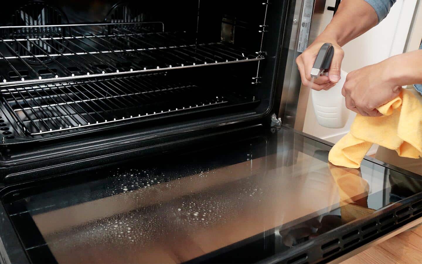 Someone spraying the glass inside an oven door. Someone spraying the glass inside an oven door.