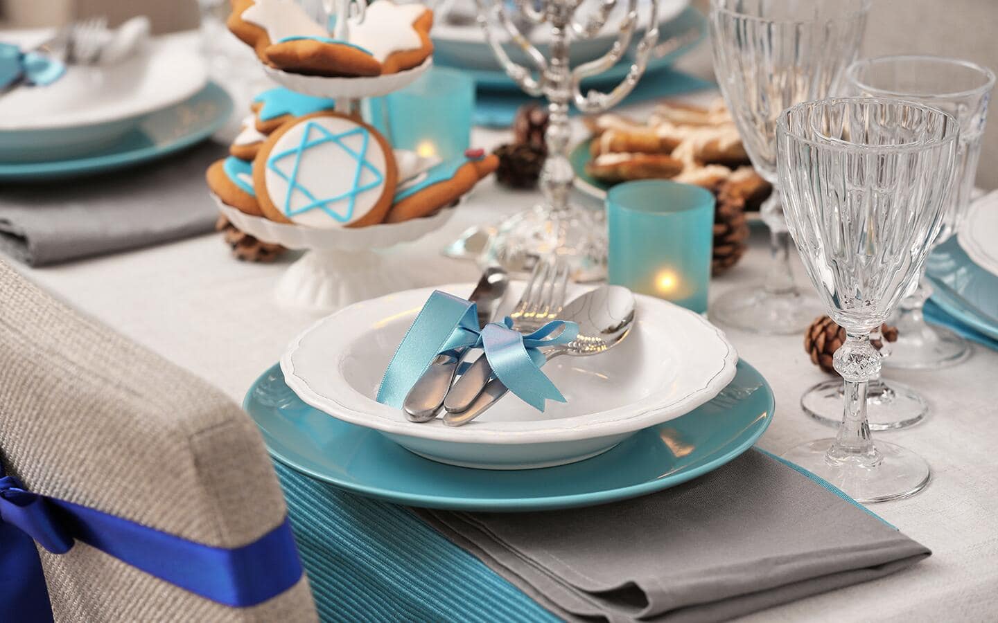 A table set with Hanukkah cookies and a chair with a blue ribbon around it.