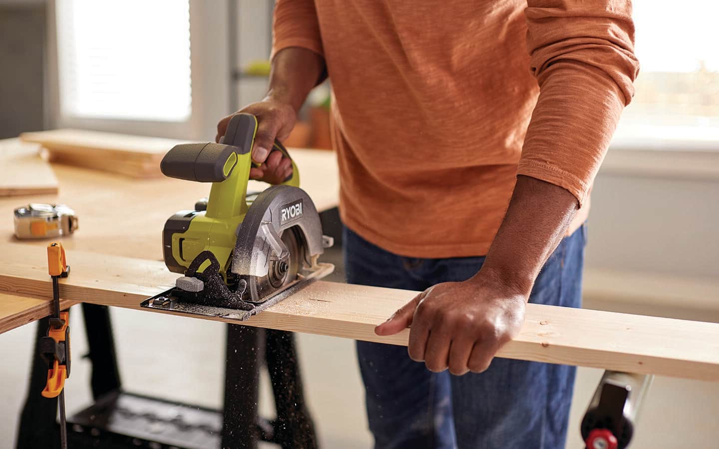 A person using a circular saw to cut a board.