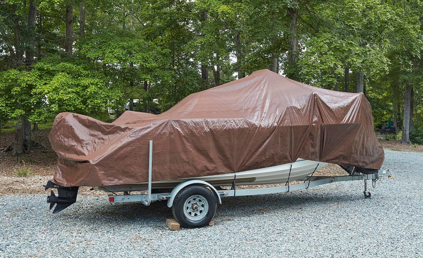 A brown, heavy-duty tarp covers a small boat.