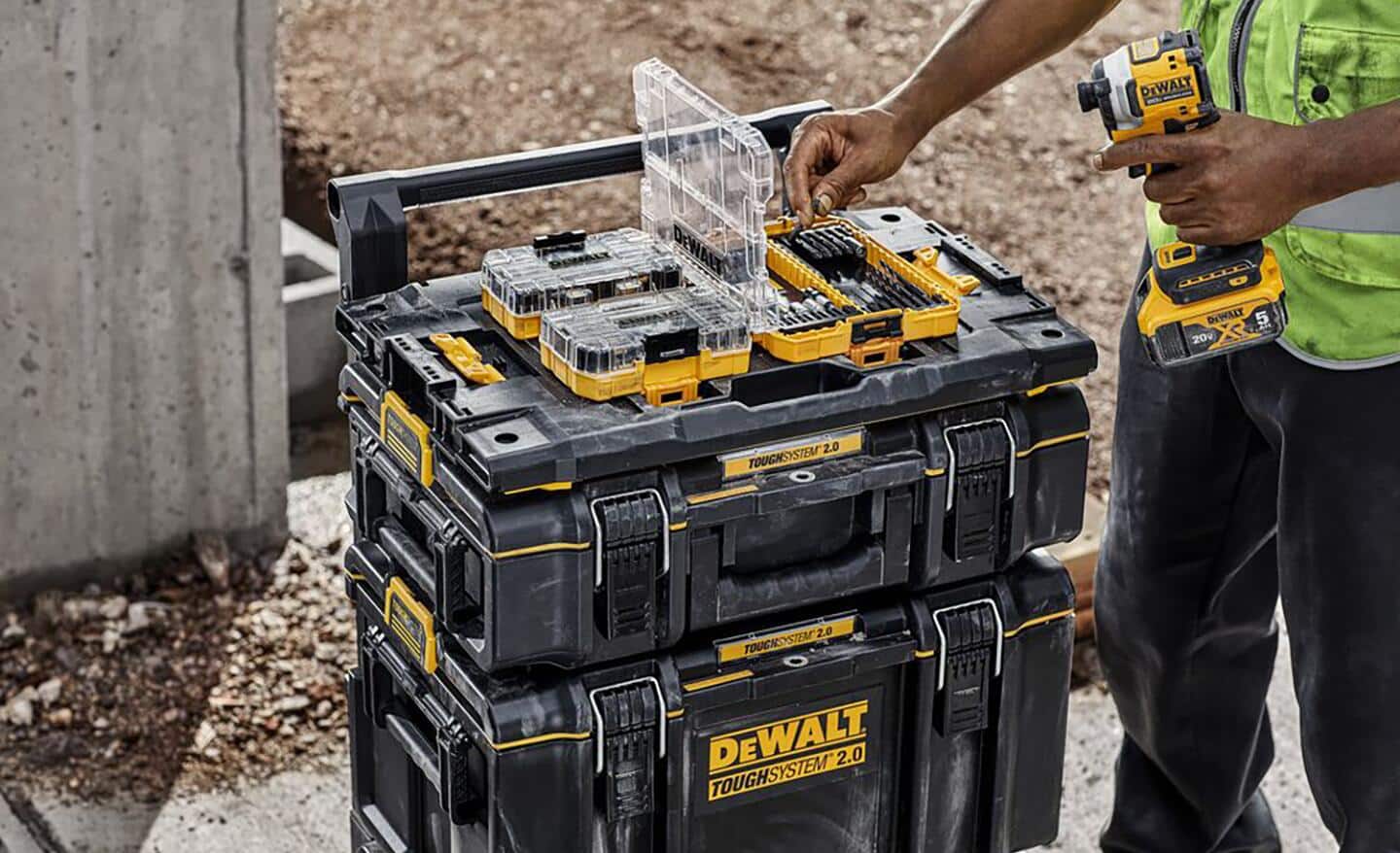 A man takes a drill bit out of case resting on a stack of tool boxes.