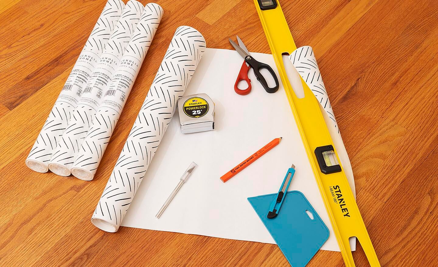 Wallpaper and tools laid out on a floor.