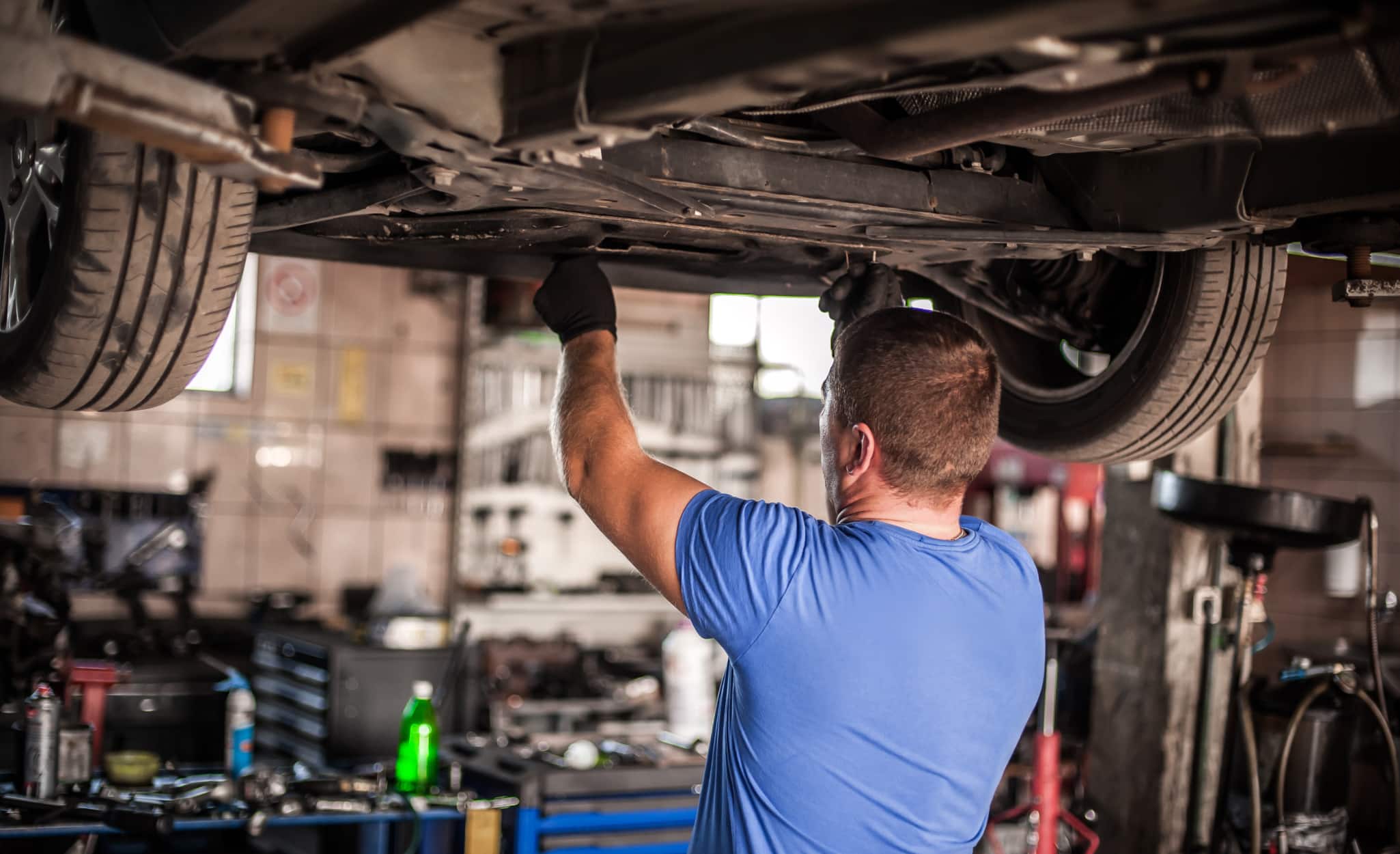 A Pro working on a vehicle raised on an auto lift. A Pro working on a vehicle raised on an auto lift.