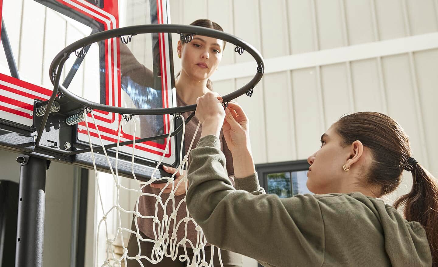 Someone hanging net onto a basketball rim.