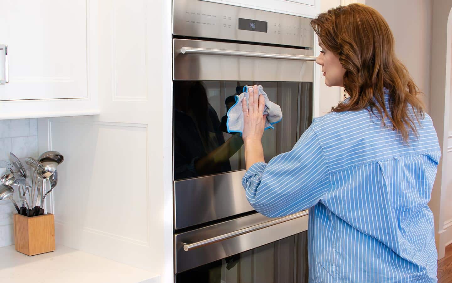 Someone cleaning the front glass door of a range.