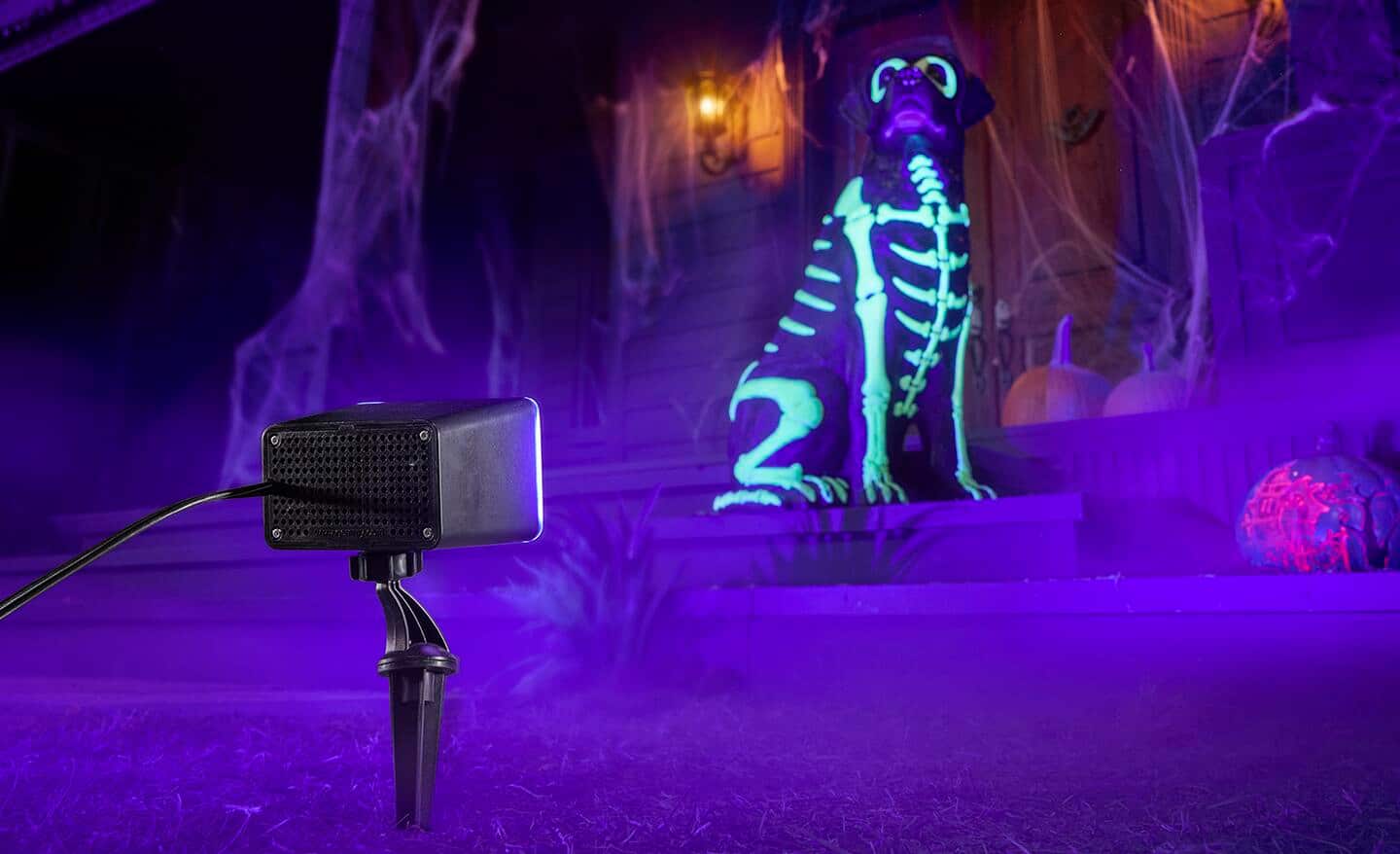 A spooky green light is projected onto yard decor for Halloween.