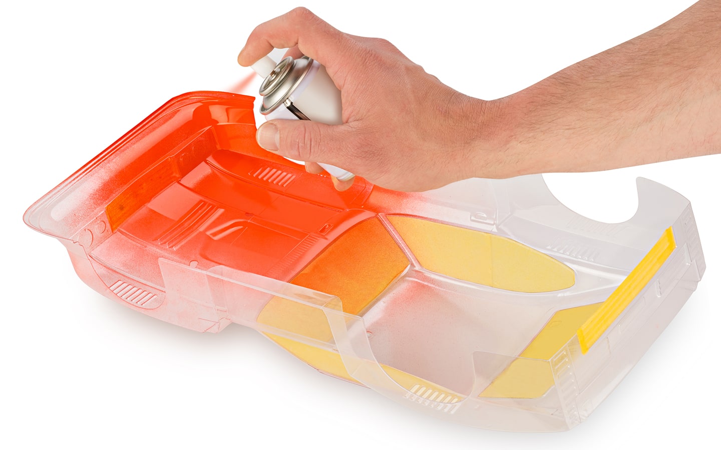 A person applying spray paint to a plastic craft piece.