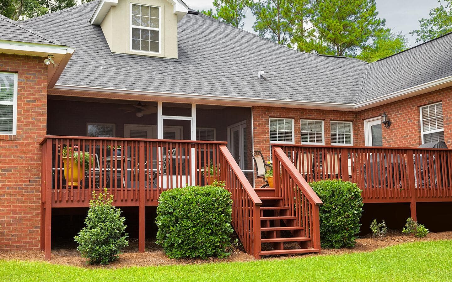 Shrubs flank a staircase leading up to a raised backyard deck. Shrubs flank a staircase leading up to a raised backyard deck.
