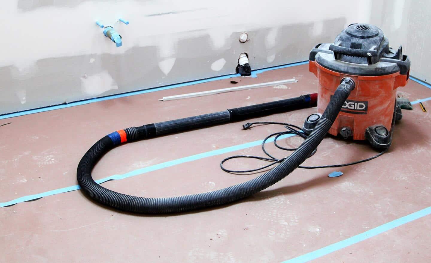 Rosin paper drop cloth taped to a floor with construction materials nearby.