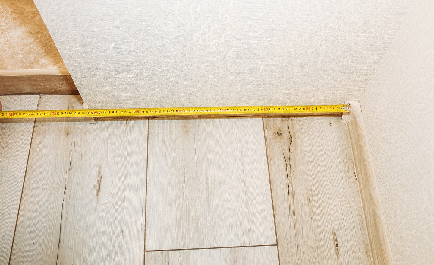 Someone measuring a corner of a room.