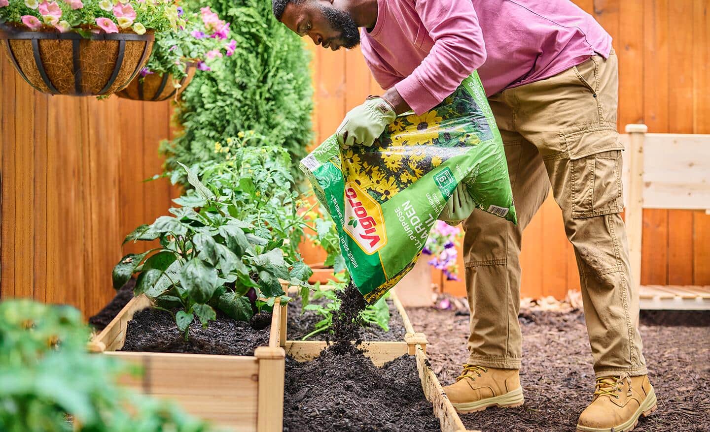 A person adds garden soil to a raised bed garden.