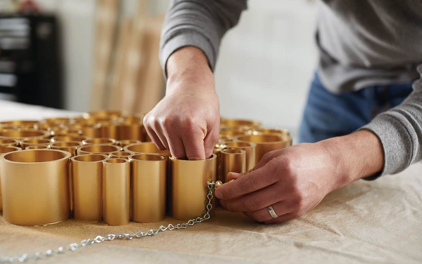 Someone attaching a hanging chain to a gold PVC pipe holiday wreath. Someone attaching a hanging chain to a gold PVC pipe holiday wreath.