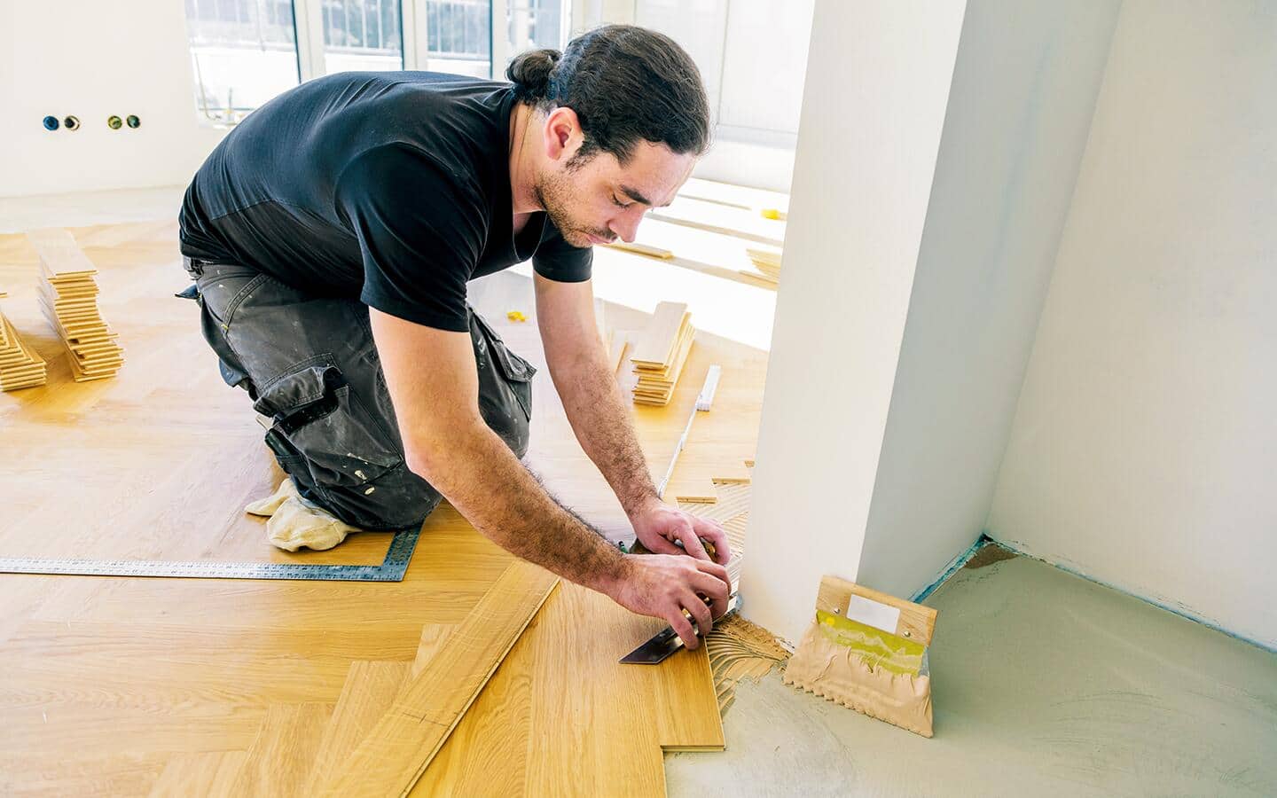 A person places a piece of trimmed tile against a wall. A person places a piece of trimmed tile against a wall.