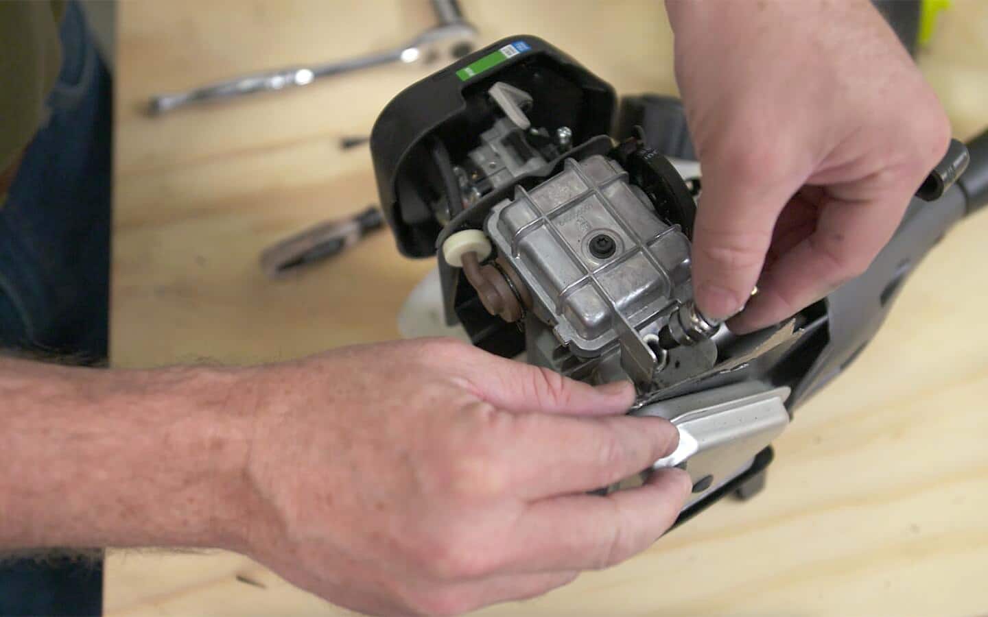 Someone adjusting a part on a string trimmer.