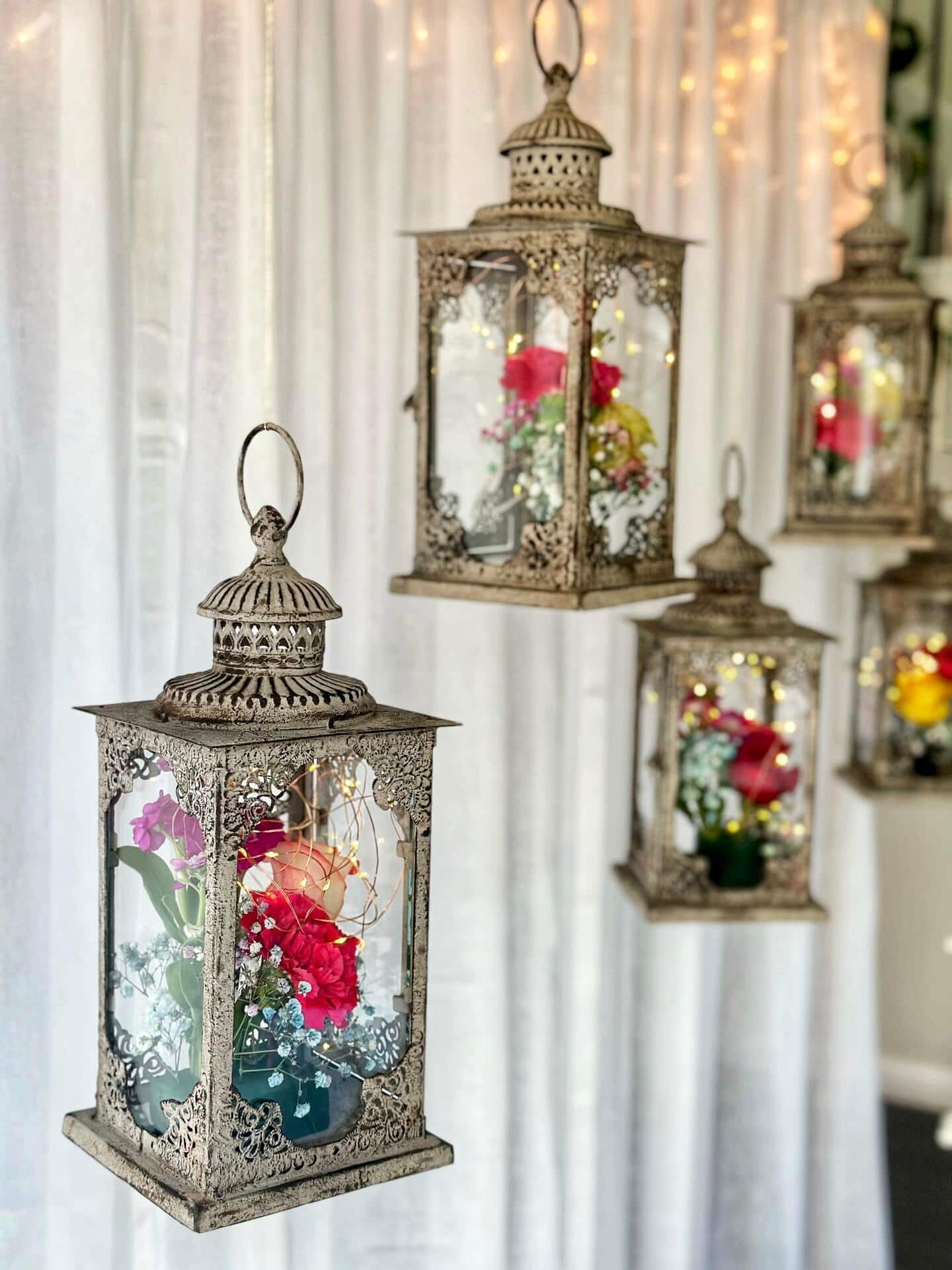 Hanging lanterns with lights and flowers inside