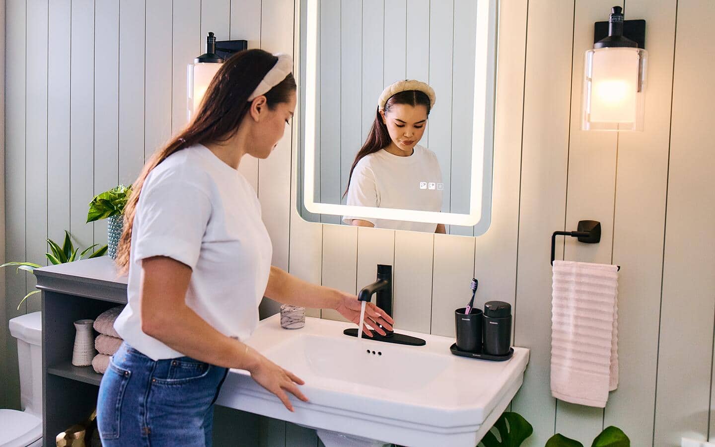 A woman uses a smart faucet in a bathroom