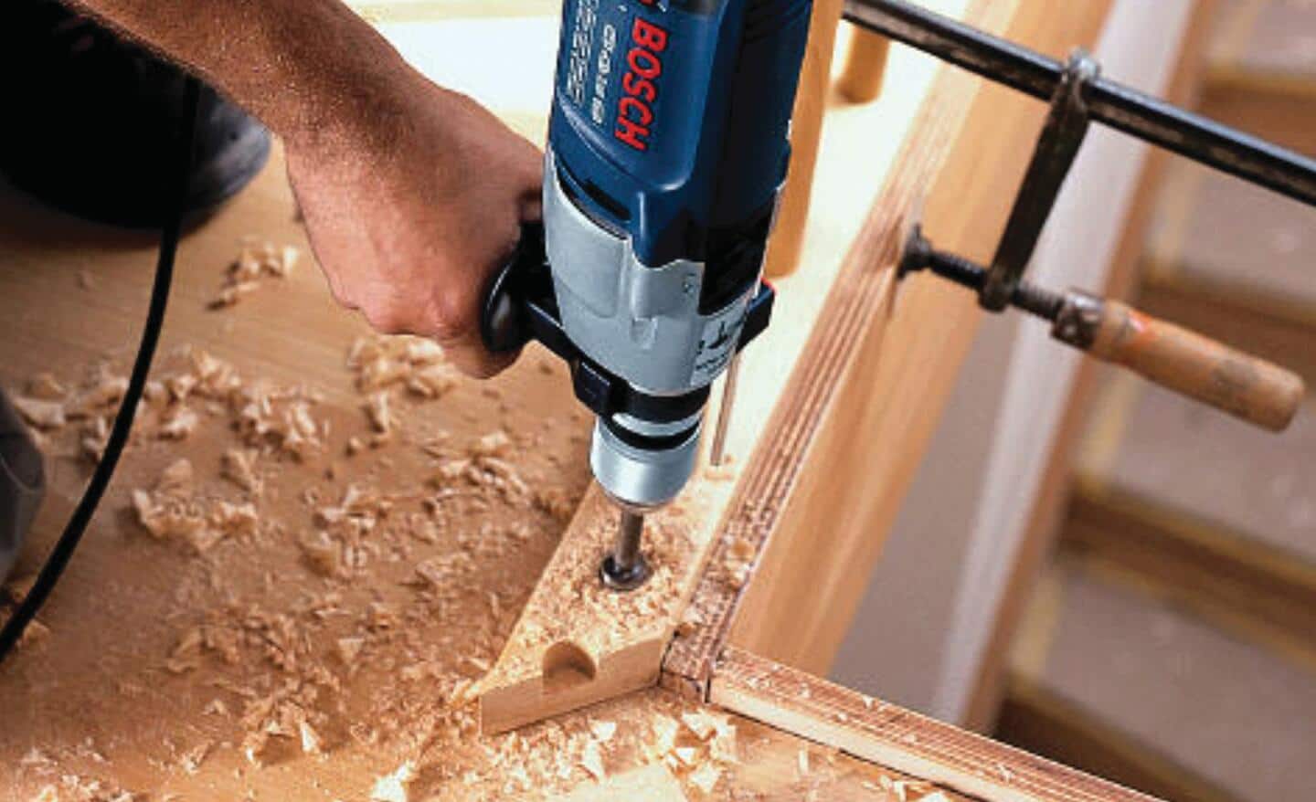 A person uses a Forstner drill bit to make a hole in a board.